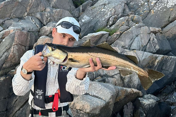 Person holding a large fish on rocky terrain