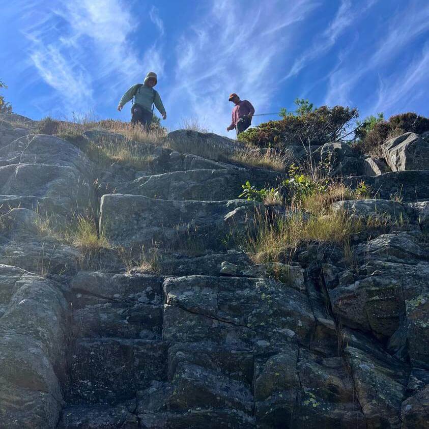 Two men with fly rods descend a rocky mark